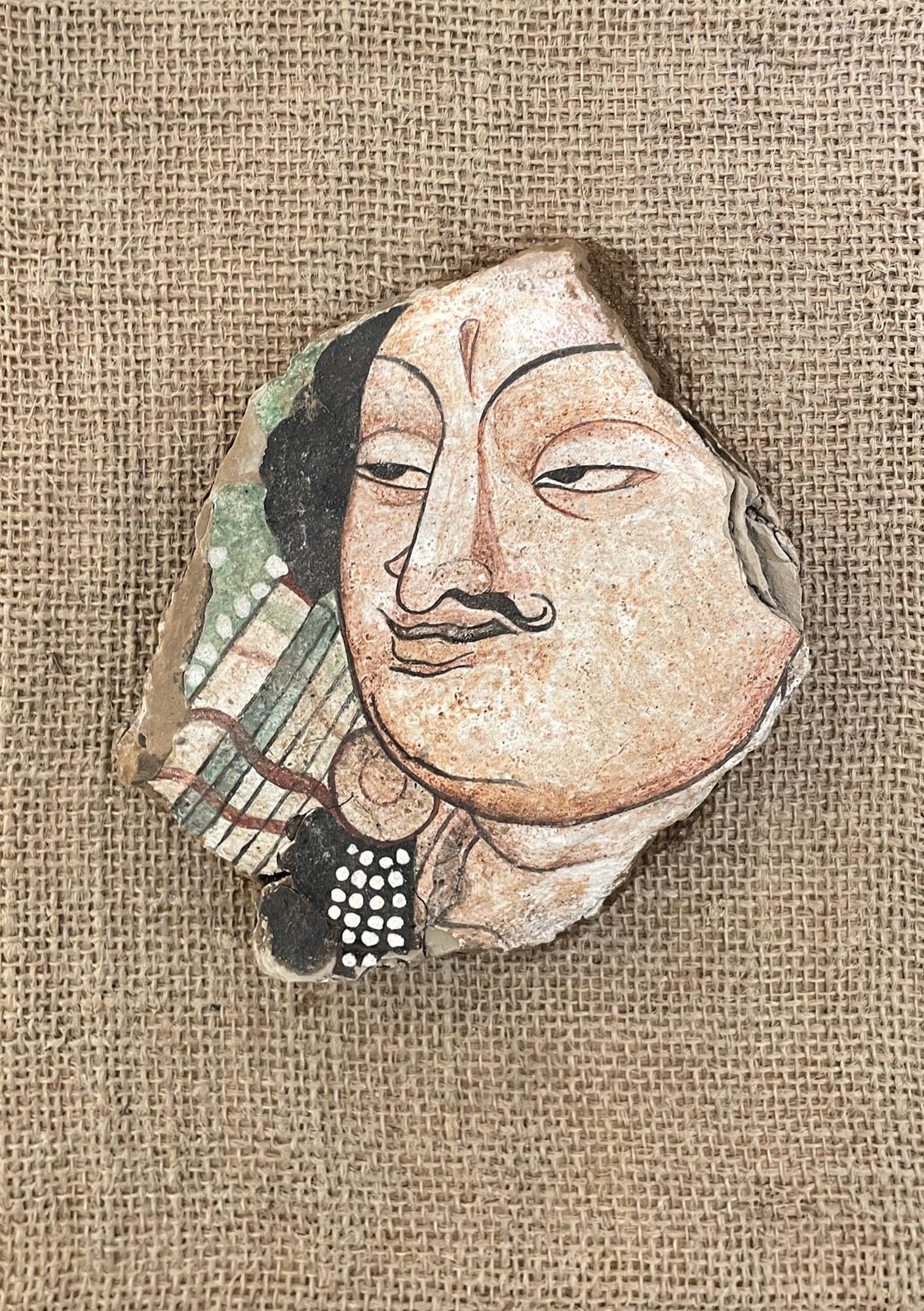 12. The Roman Merchant EN SEO Title: The Roman Merchant – Silk Road Mural on Mud-block, Jiadong Yan Meta Description: A merchant’s face painted on a natural mud-block fragment in mineral pigments and Chinese ink, drawing on ancient Silk Road cave murals. By Jiadong Yan, 20×20 cm, 2024. URL Slug: jiadong-yan-roman-merchant-mud-block-mural Keywords: Silk Road mural art, mud-block painting, cave mural replica, Jiadong Yan, mineral pigment art Alt Text: Irregular mud-block fragment painted with the face of a moustached merchant in a cave mural style, mounted on burlap TH SEO Title: The Roman Merchant จิตรกรรมฝาผนังบนก้อนดิน โดยเจียต้ง หยาน Meta Description: ใบหน้าพ่อค้าวาดบนก้อนดินธรรมชาติด้วยสีแร่และหมึกจีน ได้แรงบันดาลใจจากจิตรกรรมฝาผนังถ้ำโบราณบนเส้นทางสายไหม โดยเจียต้ง หยาน 20×20 ซม. ปี 2024 Keywords: จิตรกรรมฝาผนังสายไหม, ภาพวาดบนก้อนดิน, จิตรกรรมถ้ำโบราณ, เจียต้ง หยาน, งานศิลปะสีแร่ Alt Text: เศษก้อนดินทรงอิสระวาดใบหน้าพ่อค้าไว้หนวดในสไตล์จิตรกรรมฝาผนังถ้ำ ติดบนผ้ากระสอบ